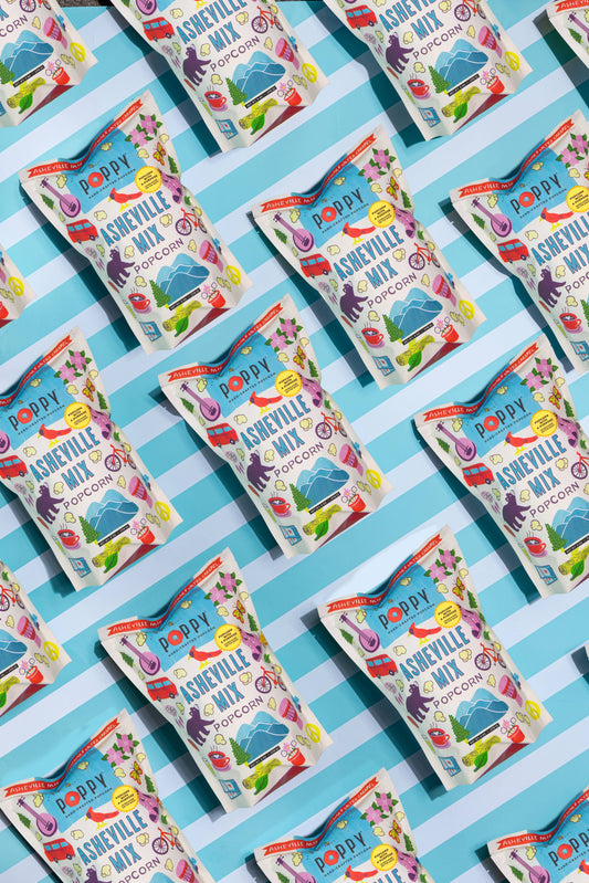 Packets of Asheville Mix candy on a blue and white striped background.  Poppy popcorn.
